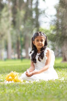 Little girl in white dress and with a cute bouquet of flowers in her hand