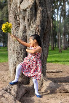 Little girl in dress celebrating in the park with a bouquet of flowers in her hand