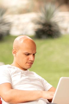 Bald man doing search from his laptop outdoor