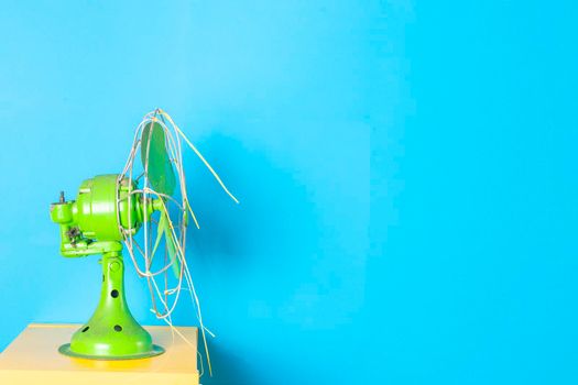 Antique green colored fan with blue background