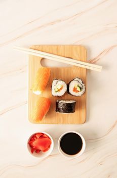 Japanese cuisine concept. Sushi salmon set on wooden cutting board. Asian food on beige marble background top view
