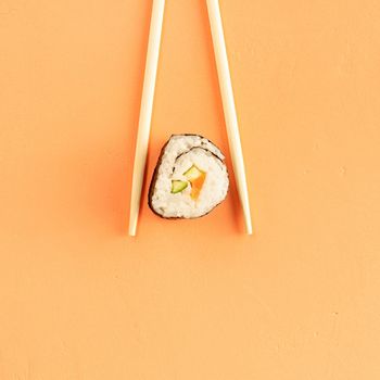 Minimal concept. Sushi rolls and chopsticks, isolated on orange background. Top view. Flat lay