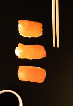 Set of sushi rolls and chopsticks, isolated on black background Top view. Flat lay