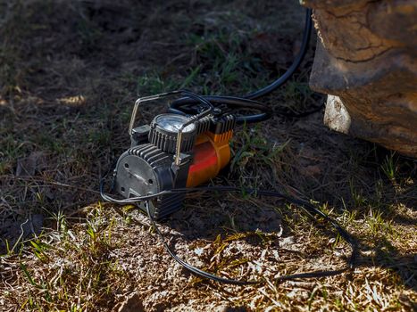 Electric compressor with gauge on ground next to tractor wheel.