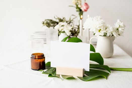 Mock up label the blank menu frame in bar restaurant, Stand for booklets with white paper, wooden tent card on monstera leaf on restaurant table