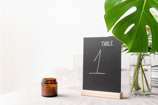 Mock up table tent with words table 1 on restaurant table with tropical bouquet. Black chalk table tent