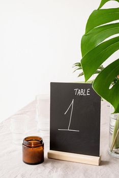 Mock up table tent with words table 1 on restaurant table with tropical bouquet. Black chalk table tent