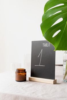 Mock up table tent with words table 1 on restaurant table with tropical bouquet. Black chalk table tent