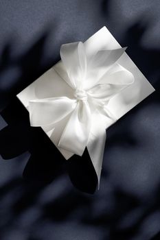 Anniversary celebration, shop sale promotion and luxe surprise concept - Luxury holiday white gift box with silk ribbon and bow on black background, luxe wedding or birthday present