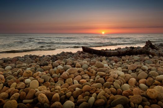 The stick on a lot of beautiful polished sea rocks in sunset and sea view