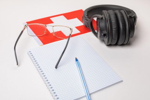 Learning foreign languages in Switzerland with audio recordings and headphones. Notepad, glasses, pen.