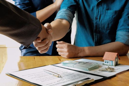 married couple and friendly realtor shaking hands after making real estate deal indoors, above view