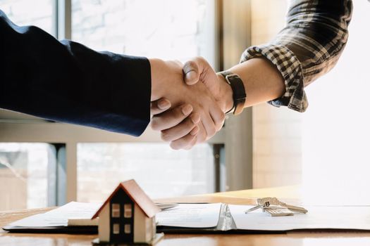 Real estate agent and customers shaking hands together celebrating finished contract after about home insurance and investment loan, handshake and successful deal.