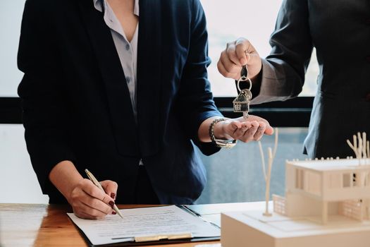 estate agent giving house keys to man and sign agreement in office.