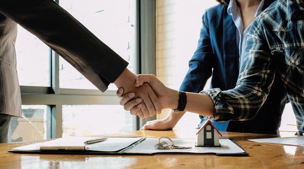 Real estate agent and customers shaking hands together celebrating finished contract after about home insurance and investment loan, handshake and successful deal.