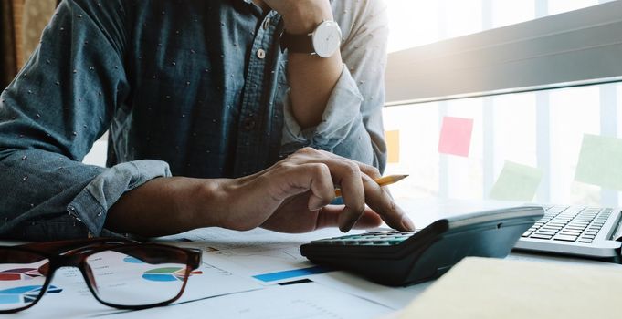 Business woman working in finance and accounting Analyze financial budget with calculator and laptop computer in the office.