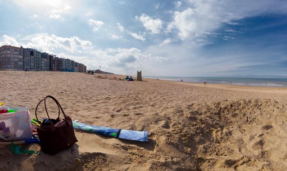 Point of view on the beach of Koksijde in Belgium on a sunny springday with some beachtoys and handbag at the side.