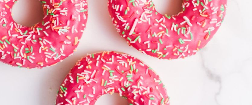 Bakery, branding and cafe concept - Frosted sprinkled donuts, sweet pastry dessert on marble table background, doughnuts as tasty snack, top view food brand flat lay for blog, menu or cookbook design