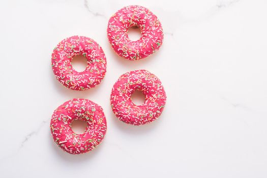 Bakery, branding and cafe concept - Frosted sprinkled donuts, sweet pastry dessert on marble table background, doughnuts as tasty snack, top view food brand flat lay for blog, menu or cookbook design