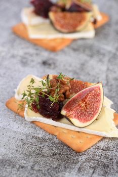 Cracker with a slice of camembert, jam, figs and nuts.
A great snack idea for a holiday, picnic or party.
