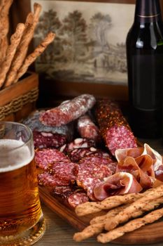 Antipasti dish with bacon, jerky, salami, crispy grissini with cheese. A meat appetizer is a great idea for a beer.