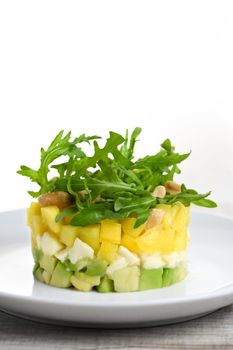 Fresh avocado, mango, mozzarella and arugula salad seasoned with nuts