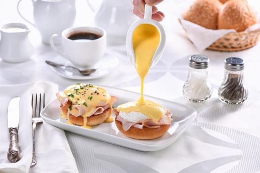 Breakfast.Best  Eggs Benedict - fried English bun, ham, poached eggs, watering Hollandaise butter sauce from the gravy boat