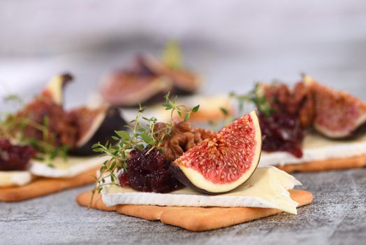 Cracker with a slice of camembert, jam, figs and nuts.
A great snack idea for a holiday, picnic or party.
