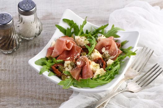 Arugula salad, prosciutto with sun-dried tomatoes, slices of mozzarella, capers, seasoned with olive butter and parmesan. A dish for those who monitor their health