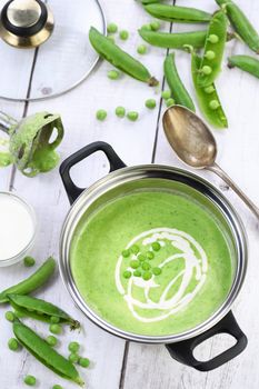 Saucepan of freshly cooked soup of mashed green peas and cream on the table.