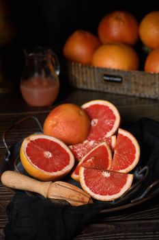 Slices of fresh grapefruit prepared for making fresh squeezed juice on a platter, dark background