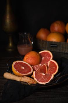 Slices of fresh grapefruit prepared for making fresh squeezed juice on a platter, dark background