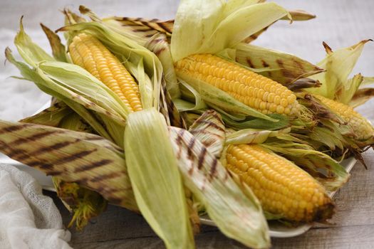 Delicate, juicy corn on the cob in husk cooked grilled