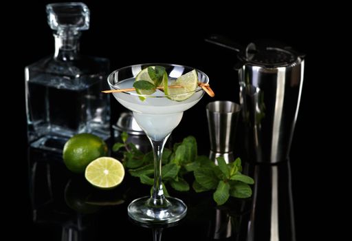 Tequila, Citrus liquor, lime juice - this is a Margarita cocktail. A  of lime with a sprig of mint decorates a glass. Dark  moody food