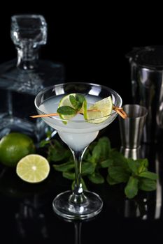 Tequila, Citrus liquor, lime juice - this is a Margarita cocktail. A  of lime with a sprig of mint decorates a glass. Dark  moody food