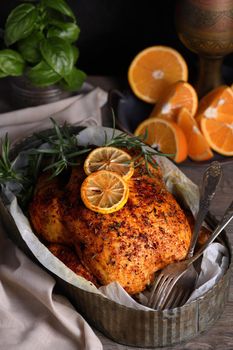 Baked whole chicken in spices with crispy appetizing fried crust in a tray, dark moody  