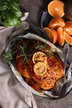 Baked whole chicken in spices with crispy appetizing fried crust in a tray, dark moody  