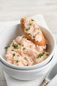 Salmon paste bowl with soft cheese and herb, toasted sliced ​​bread, vintage knife with a textile napkin on a wooden table