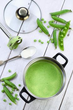 Saucepan of freshly cooked soup of mashed green peas and cream on the table.