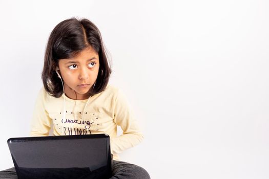 Cute little girl is using her notebook and headphones