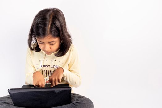 Cute little girl is using her notebook and headphones