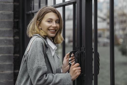 Young woman at the entrance to the park at the metal gate