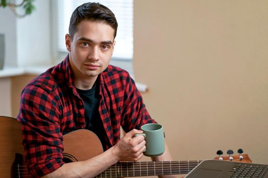 Man on kitchen playing the guitar with laptop at home