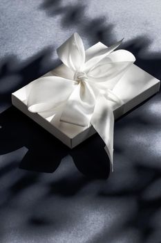 Anniversary celebration, shop sale promotion and luxe surprise concept - Luxury holiday white gift box with silk ribbon and bow on black background, luxe wedding or birthday present