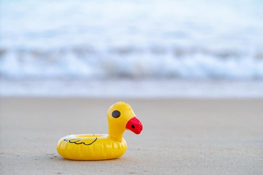 Yellow rubber duck on the seashore in the morning, sand beach.