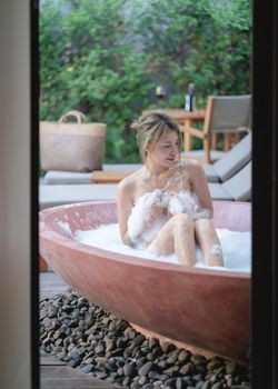 Woman playing with bubble foam while taking a bath at bathtub.