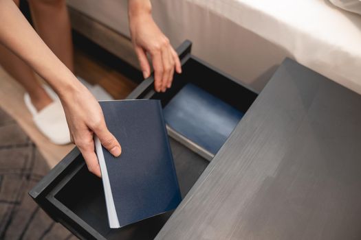 Woman hand with wooden drawer stand and note book inside.