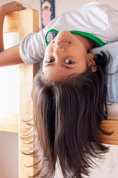 A girl is upside down looking down from the top of her bunk