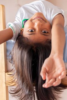 A girl is upside down looking down from the top of her bunk