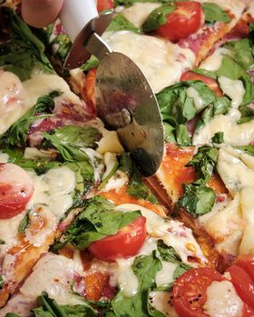 Pizza with cheese, tomatoes, spinach and smoked sausage